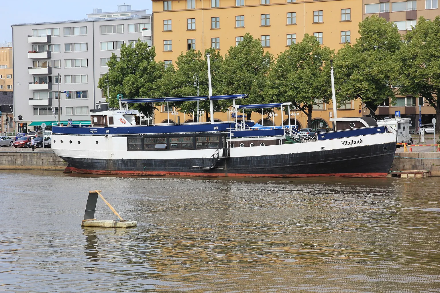 Kannettava tietokone kotityöpisteellä, ikkunasta näkyy Turun joen ranta syysvalossa
